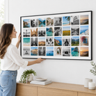 Une femme accroche la toile photo Instawall Canvas Wide avec cadre baklijst noir au mur